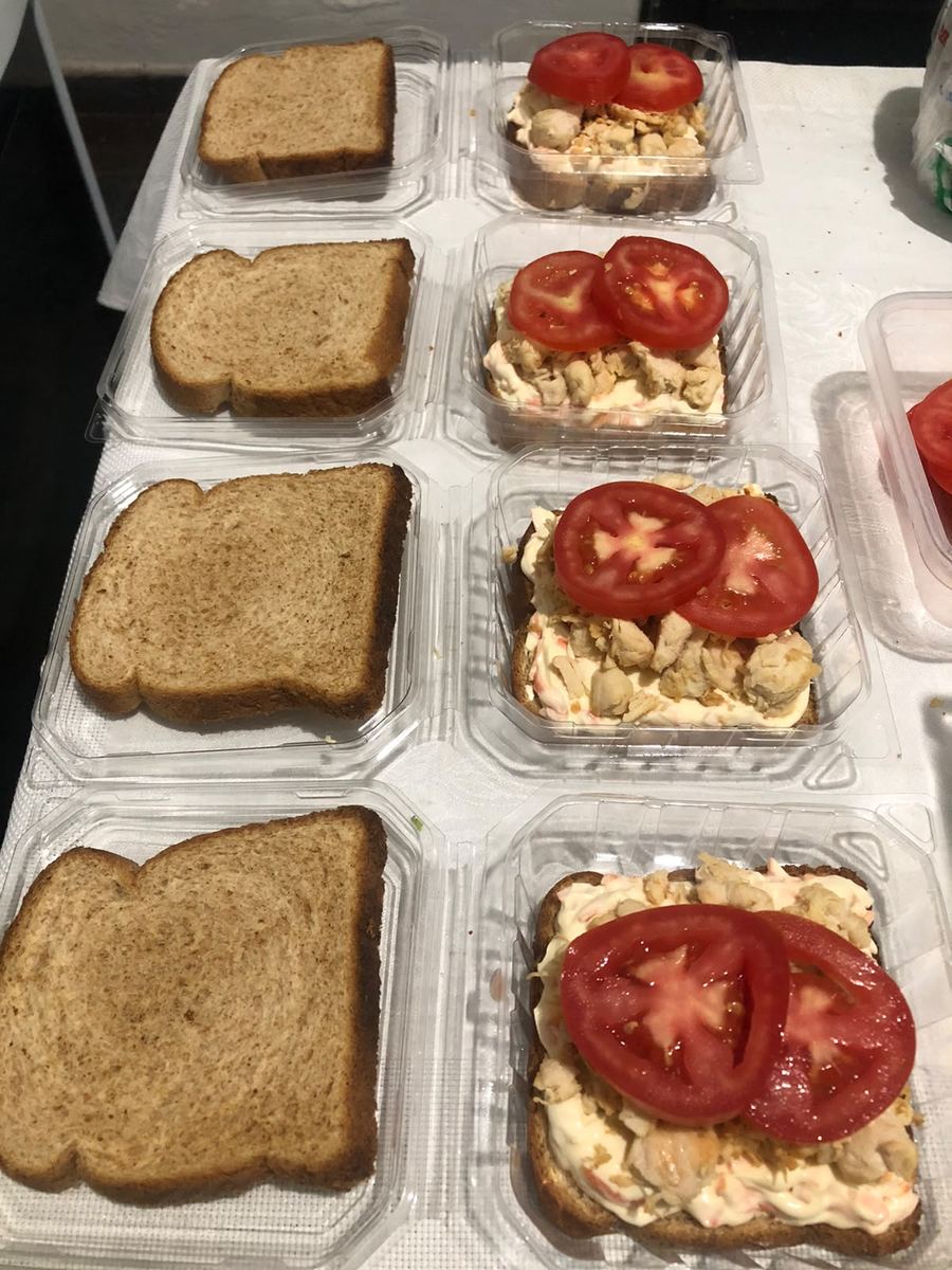 Lanches de frango sendo montados em linha, com tomate